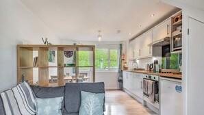 Une cuisine moderne avec des meubles blancs, un four encastré et une fenêtre donnant sur un espace verdoyant.