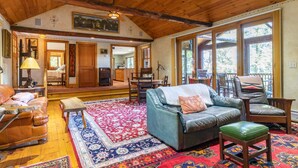 A cozy living room with a leather sofa, a matching ottoman, and a patterned rug. - Rustic and luxurious 4 bedroom house on secluded NH lake! (Pittsfield)