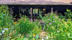 A rustic building with a garden full of various plants and flowers. - Rustic and luxurious 4 bedroom house on secluded NH lake! (Pittsfield)