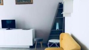 Ein modernes Wohnzimmer mit einer weißen Unterhaltungsecke, einem gelben Sofa und einer Treppe.