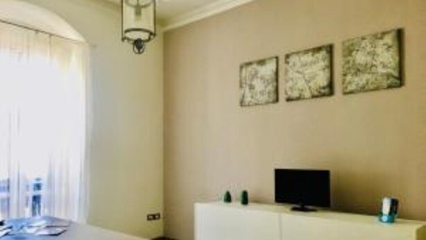 Ein Zimmer mit einem Esstisch, einer weißen Kommode mit Fernseher und drei gerahmten Kunstwerken an der Wand.