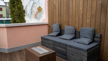 A wooden bench with cushions, a small table, and a wall with a mural.