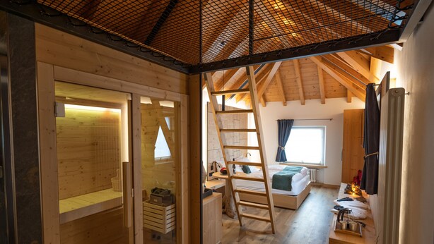 Una cabaña acogedora con habitación en un entrepiso, pisos de madera, una escalera al espacio para dormir superior y un pequeño rincón de trabajo.