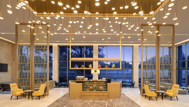 A modern lounge area with a central counter, seating arrangements, and a view of the outdoors.