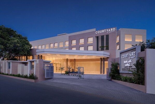 Une entrée d’hôtel moderne, avec une enseigne indiquant « Courtyard by Marriott » et une galerie couverte.