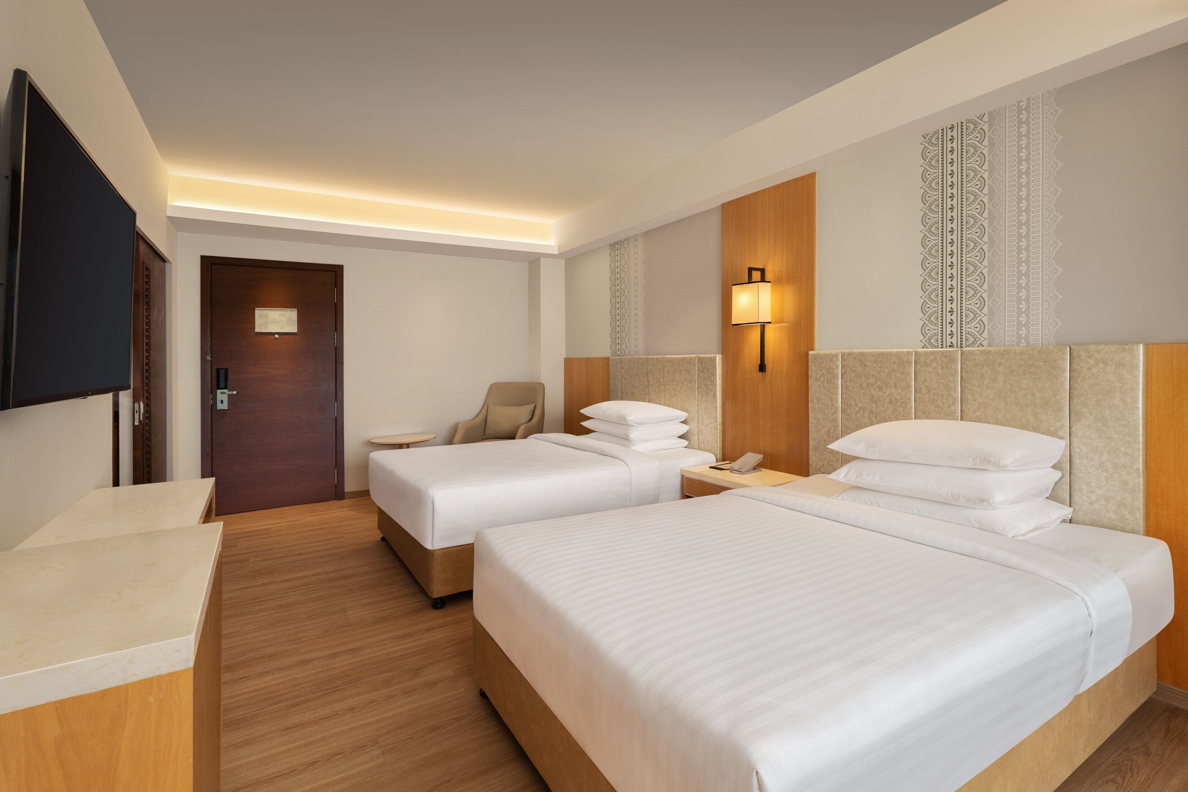 A hotel room with two beds, a TV, a desk, and a chair.