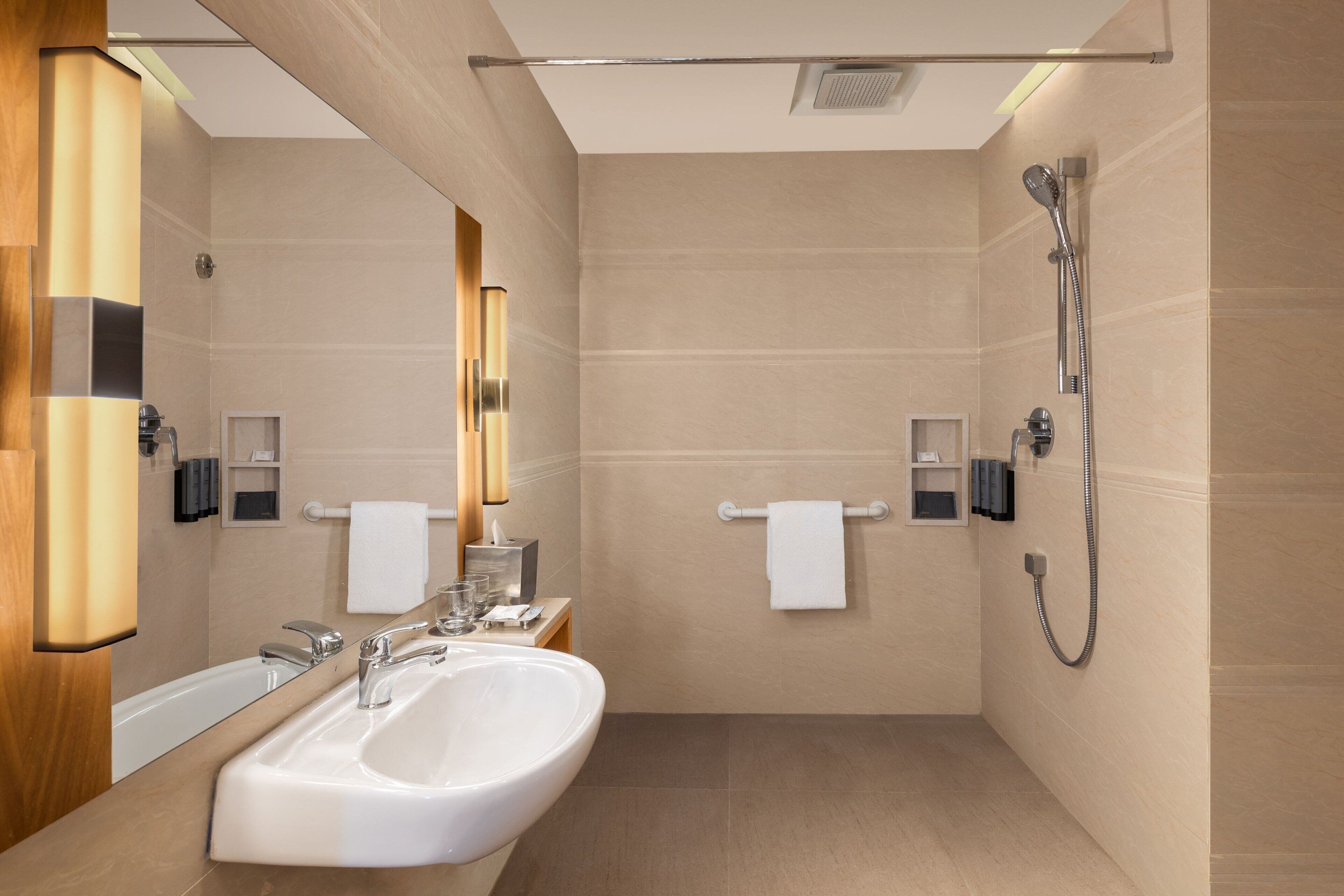 Ein modernes Badezimmer mit einem großen Waschbecken, einem Spiegel und einer Dusche.