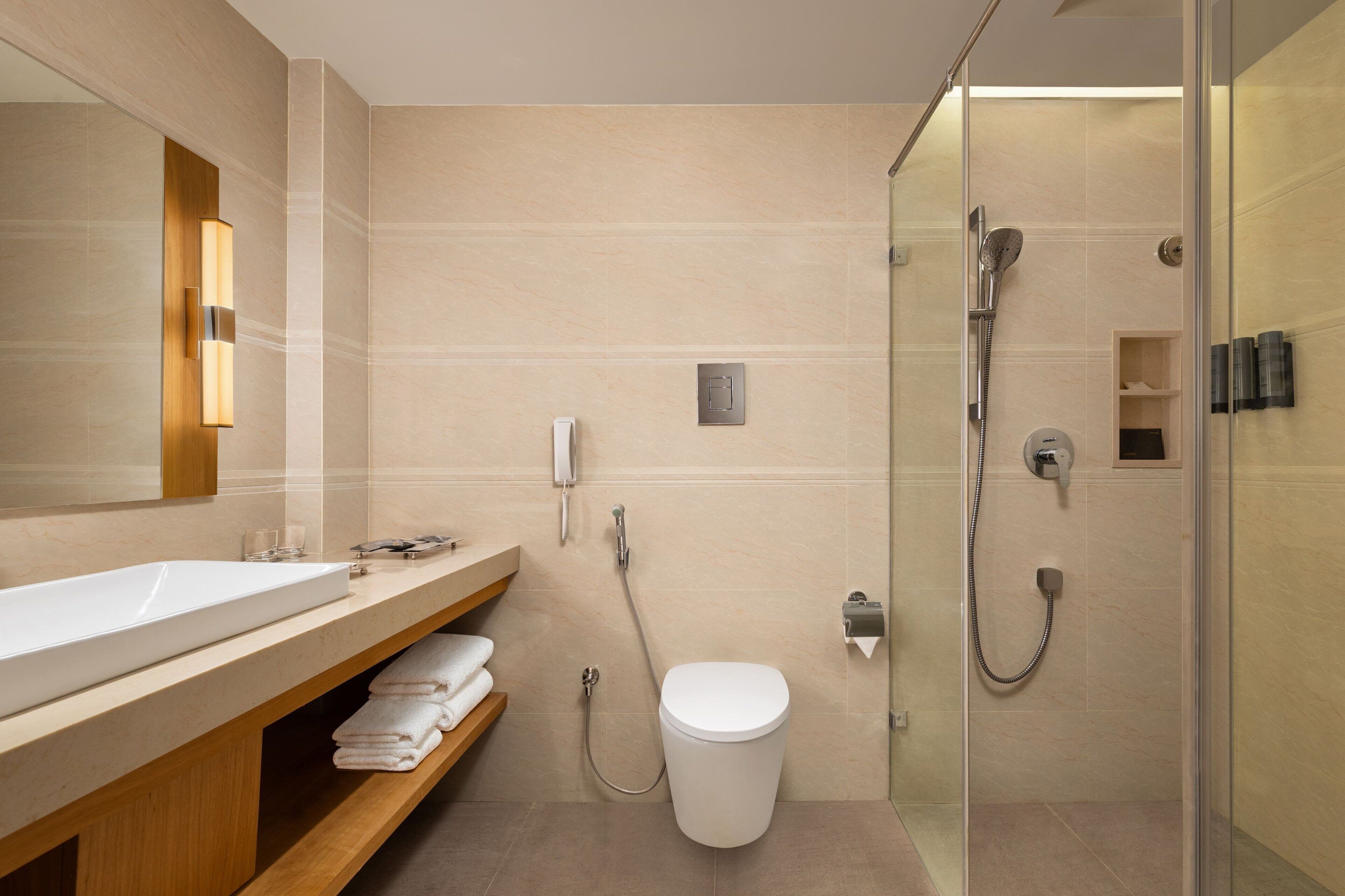 A modern bathroom with a large sink, a toilet, and a glass-enclosed shower area.