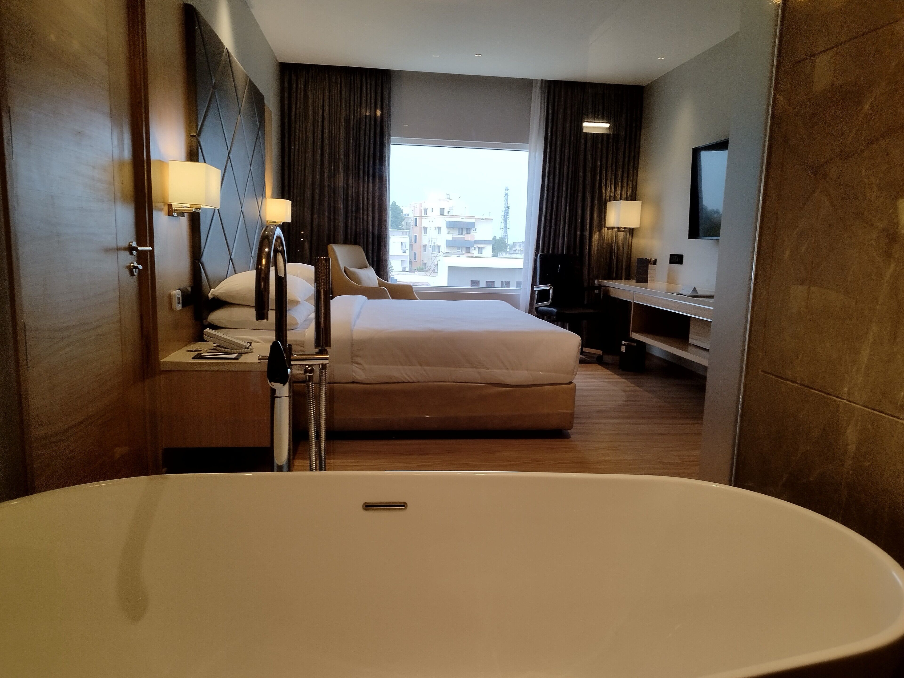 Habitación de hotel con una bañera grande, una cama, un escritorio y una silla.