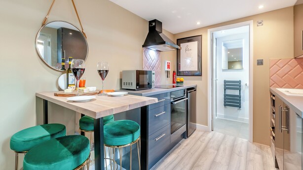 Une cuisine moderne dotée d’un îlot central, de tabourets de bar, d’un four à micro-ondes et d’un réfrigérateur.