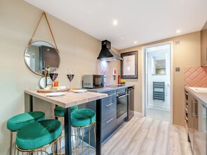 A modern kitchen with a central island, bar stools, a microwave, and a refrigerator.