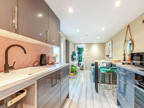 A modern kitchen with a large island, stainless steel appliances, and a view into the living area.