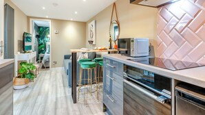 Une cuisine moderne équipée d’un four à micro-ondes, d’un four traditionnel et d’une hotte intégrée. Un coin repas avec une table et des chaises est également disponible.