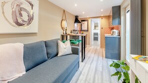 A modern living room with a grey sofa, a coffee table, and a large abstract painting. - Vitamin Sea Residency (Herne Bay)