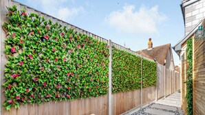 A narrow outdoor pathway with a wooden bench, a wooden fence with climbing plants, and a stone-tiled path. - Vitamin Sea Residency (Herne Bay)