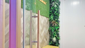 A bathroom with a glass shower enclosure, a wooden bench, and a wall-mounted plant display. - Vitamin Sea Residency (Herne Bay)