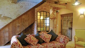 Un salon chaleureux avec un canapé à motifs, un escalier en bois et un mur en briques au style rustique.