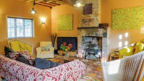 Un salon confortable avec un canapé, des fauteuils, une cheminée et un téléviseur.