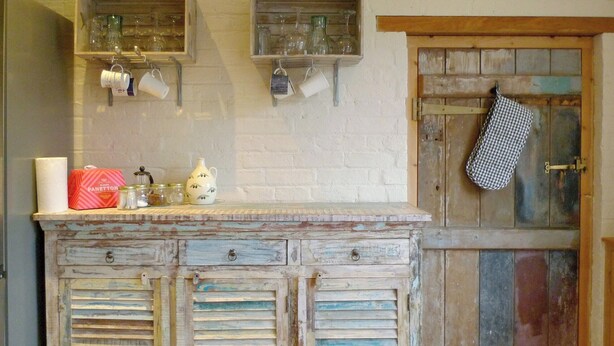 A rustic kitchen with a wooden cabinet, a hanging kitchen towel, and various kitchen items on the counter. - 2 bedroom accommodation in Beeby (Beeby)