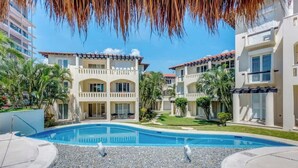 Un hotel con piscina, varios balcones y cielo despejado.