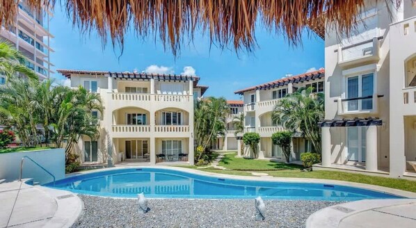A hotel with a swimming pool, multiple balconies, and a clear sky. - Steps to 5th Ave, Beach, with Pool Access & Gazebo (Playa del Carmen)