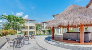 A resort with a pool area, outdoor seating, and a thatched-roof structure.