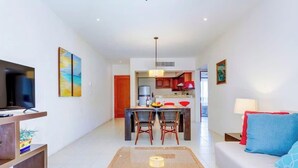 Una sala de estar moderna con un sofá, un televisor y un comedor con sillas y una mesa.
