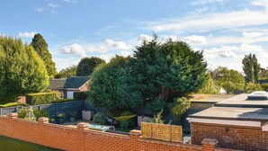A residential area with a brick wall, a fenced garden, and a house with a sloped roof. - 2 bedroom accommodation in West Mersea (West Mersea)