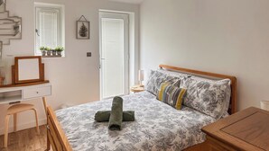 A bedroom with a wooden bed, a desk, and a chair. - 2 bedroom accommodation in West Mersea (West Mersea)