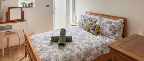 Quarto com cama de madeira, uma escrivaninha e uma cadeira.