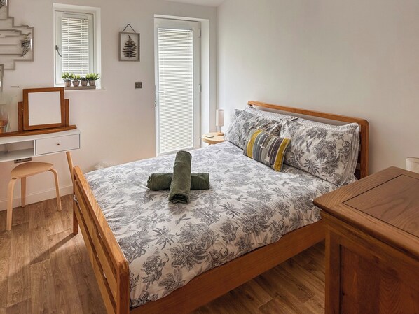 A bedroom with a wooden bed, a desk, and a chair.