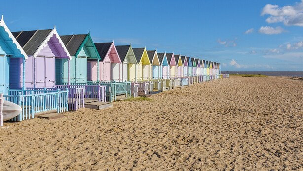 A row of colorful beach huts along a sandy beach. - 2 bedroom accommodation in West Mersea (West Mersea)
