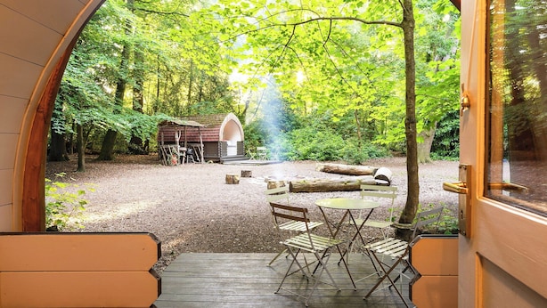 A wooden archway leading to an outdoor seating area with a table and chairs, surrounded by trees and a small wooden structure. - 1 bedroom accommodation in Woolton Hill, nr Newbury (Woolton Hill, nr Newbury)