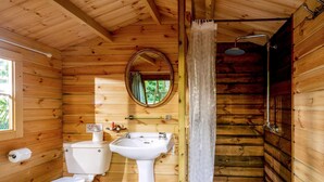 A wooden cabin bathroom with a toilet, sink, shower, and a window. - 1 bedroom accommodation in Woolton Hill, nr Newbury (Woolton Hill, nr Newbury)