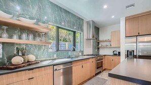 Una cocina moderna con armarios de madera, lavavajillas de acero inoxidable y un ventanal grande.