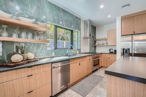 Eine moderne Küche mit Marmor-Spritzschutz, Holzschränken und Edelstahlgeräten.