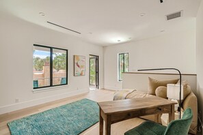 Una habitación moderna con un ventanal grande, una mesa de madera, un sofá y una alfombra verde.