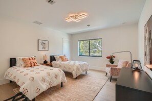 Ein Schlafzimmer mit zwei Betten, einem Schreibtisch und einem Fenster mit Blick.