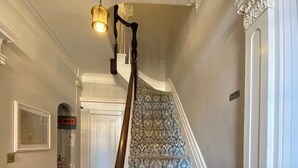 A staircase with patterned carpet, a wooden handrail, and a wall-mounted light fixture. - Townhouse Apt 2 w Parking in Downtown Portsmouth (Portsmouth)