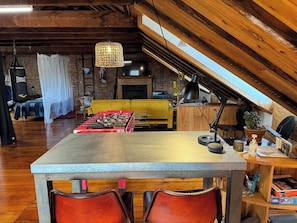 Une chambre mansardée avec un baby-foot, une télévision, un canapé et un plafond en bois.
