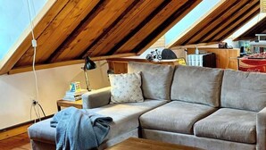 A cozy loft bedroom with a sloped ceiling, a grey sofa, a wooden coffee table, and a patterned armchair. - Townhouse Apt 2 w Parking in Downtown Portsmouth (Portsmouth)