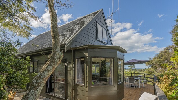 Une maison moderne dotée d’une grande terrasse, d’un espace salon extérieur abrité et offrant une vue sur le paysage environnant.