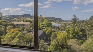 Une vue depuis une fenêtre donnant sur un quartier résidentiel avec des maisons, des arbres et un lac.
