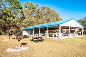 A covered picnic area with picnic tables and a barbecue grill. - Harbourside II (New Bern)