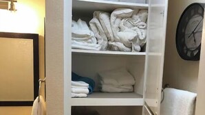 Ein Hotelbad mit Spiegel, Waschbecken und Regalen mit Handtüchern und Pflegeprodukten.