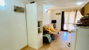 A compact living space with a sofa, a small cabinet, and a television. - I Geranei 2 San Teodoro Centro (San Teodoro)