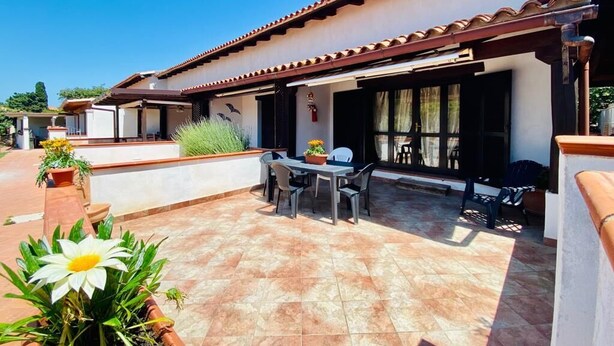 A patio area with a table and chairs, a barbecue grill, and potted plants. - I Geranei 2 San Teodoro Centro (San Teodoro)
