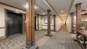 A hotel corridor with wooden columns, carpeted floors, and a door at the end. - Granby Ranch Haven: Outdoor Pool & Biking Fun (Granby)