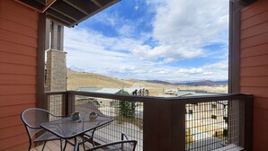 A balcony with a table and chairs, overlooking a hilly landscape. - Granby Ranch Haven: Outdoor Pool & Biking Fun (Granby)