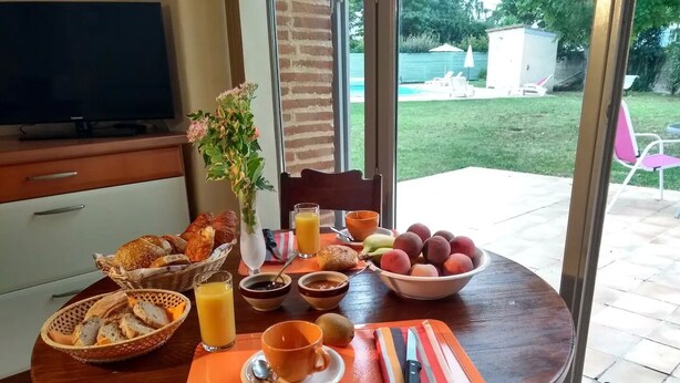 Een ontbijttafel met brood, fruit en drankjes.